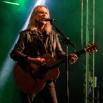 Justin Sullivan (New Model Army) on stage playing guitar and singing.