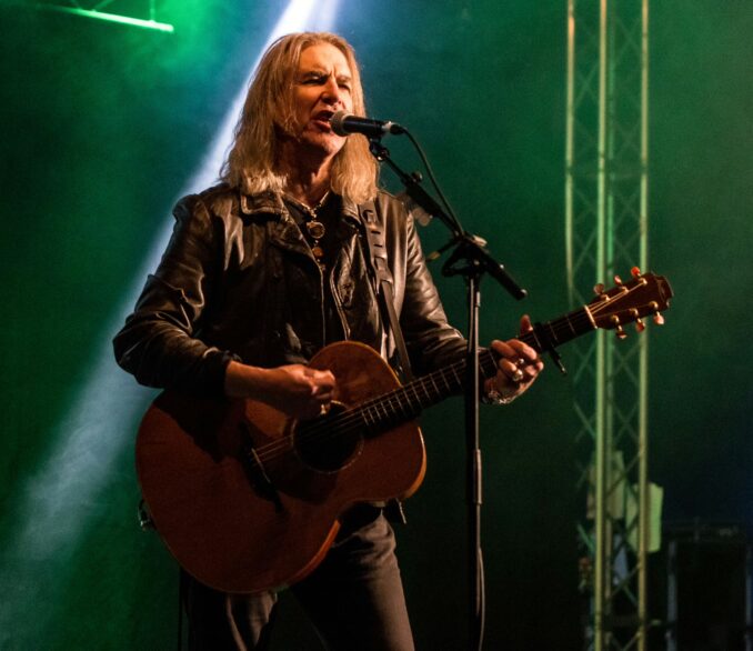 Justin Sullivan (New Model Army) on stage playing guitar and singing.